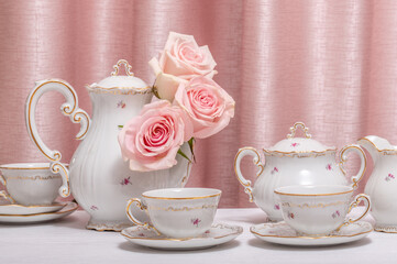 Coffee set on white wooden table with live flower heads of pink roses on pink background.