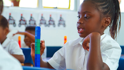 Young Girl Stacking Colorful Blocks in Classroom During Afternoon Learning Activity
