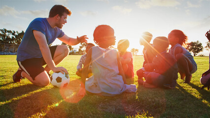 Teacher Engaging With Children During Soccer Practice at Sunset in a Park