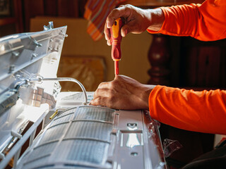 Hand of technician use a screwdriver to tighten the air conditioning assembly nuts, Air conditioning technicians Prepare to  install new air conditioner in homes.