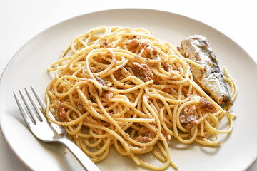 Pasta sardines with a fork on a plate. Spaghetti with canned sardine. 