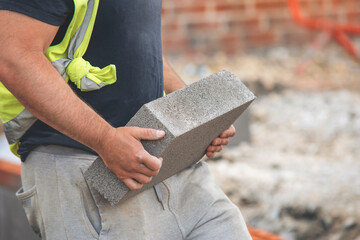 Construction worker carrying concrete block on building site during early morning hours