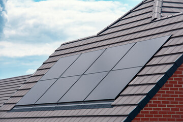 Solar panels installed on modern house roof under bright blue sky