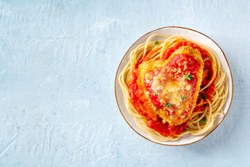 Chicken Parmesan, Italian pasta dish. Breaded chicken breast with cheese and spaghetti with tomato sauce, overhead flat lay shot with a place for text