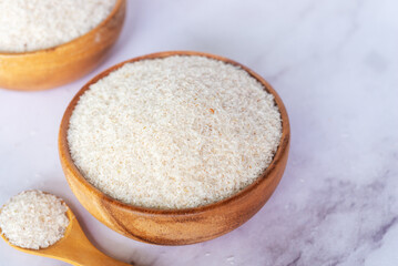 spyllium husk in wooden bowl on white marble table background.