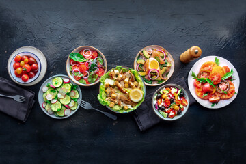 Fresh salads, overhead flat lay shot of an assortment. Variety of plates and bowls with green vegetables. Healthy food, top shot, with copy space