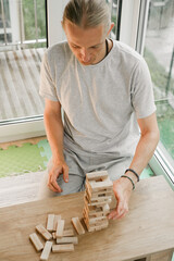 Man player balances wooden blocks, trying not to topple the tower in a competitive game setting