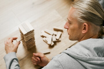 Man player balances wooden blocks, trying not to topple the tower in a competitive game setting