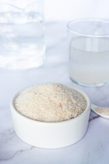 spyllium husk in white ceramic bowl on white marble table background.