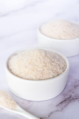spyllium husk in white ceramic bowl on white marble table background.