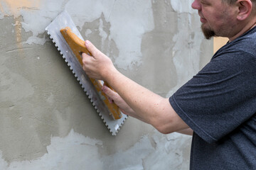 A skilled tradesman meticulously spreads plaster over a wall, ensuring a flawless finish as the...