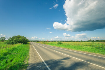 A road with a tree on the side and a clear blue sky