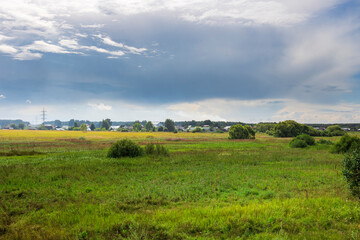 Obraz premium A vibrant expanse of green fields stretches under a dynamic sky, where sunlight dances on the landscape, infusing the countryside with life and tranquility.