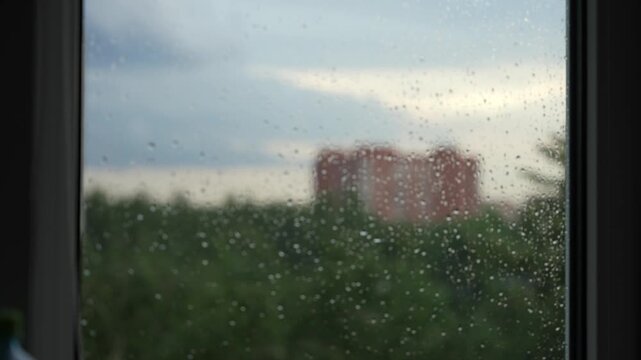 Raindrops on a window against the background of a picturesque landscape of the city, refocusing the image