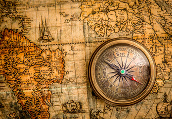 Vintage still life. Vintage compass lies on an ancient world map of 1565. Vintage style travel and adventure.