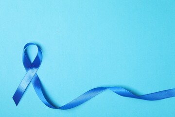 Blue ribbon on color background, top view with space for text. Prostate cancer awareness