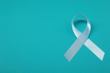 Prostate cancer awareness. Light blue ribbon on teal background, space for text