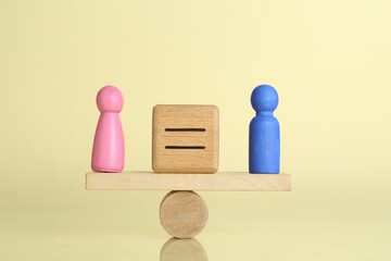 Gender equality concept. Cube with equals sign between male and female figures on scales against light yellow background