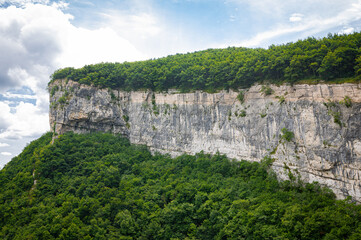 Vertical bare rock face with green vegetation below and above, characteristic of the landscape of...