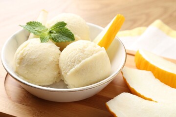 Scoops of tasty melon sorbet with mint in bowl and fresh fruit on table, closeup