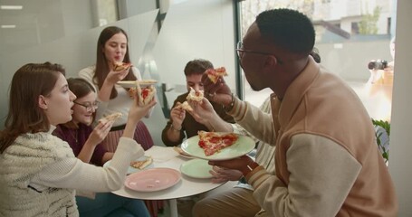 Mixed race, business team enjoying a pizza lunch break in modern office, bonding over food.
