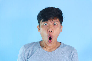 Shocked face of Asian young man in grey t-shirt on a isolated background.