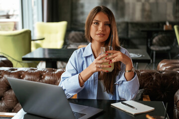 Enjoying the drink. Beautiful woman with laptop is in the bar