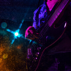Fototapeta premium Intensity of live music captured in guitarist's hand, bathed in vibrant hues of stage lights as he strum strings. Concept of music and party, hobby and work, energy, music festivals. Ad