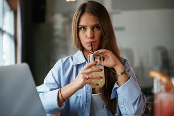 Enjoying the drink. Beautiful woman with laptop is in the bar