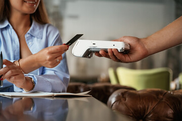 Side view. Woman is paying for the service in the restaurant
