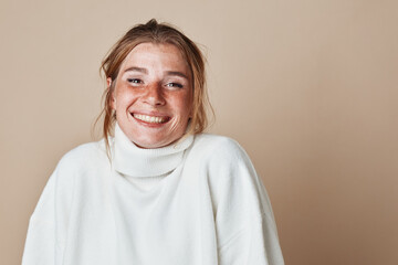 Smiling woman in white turtleneck sweater standing in front of beige wall beauty and fashion concept