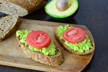 a cutting board with healthy avocado toasts with slices of tomato