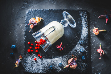 Original serving of the dessert panna cotta with lingonberries, blueberries in a glass lying on a...
