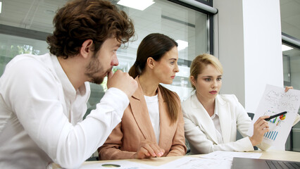 Colleagues in a modern office consult each other, planning project details and financial strategies. Ideal for teamwork, project management, and business planning themes.