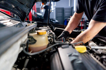close up in a car service center master in a black T-shirt using tools unscrews the bolts in the...
