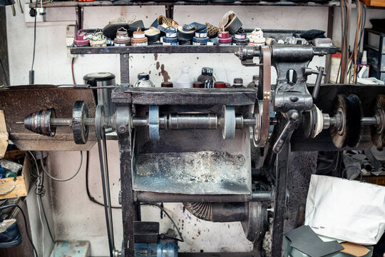 antique flat shoe repair and polishing machine closed in a messy and dirty former shoe workshop. No people