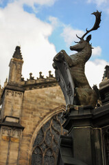 Fototapeta premium Historic stag statue by Gothic cathedral under blue sky with scattered clouds