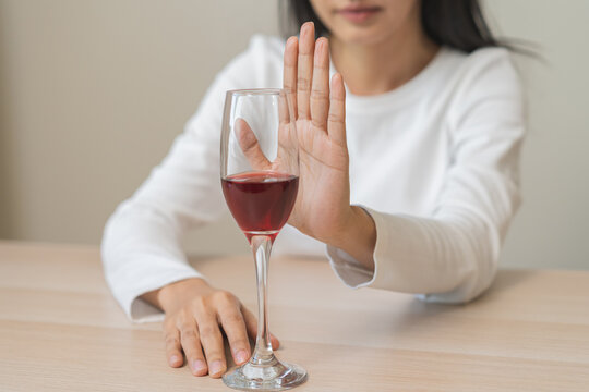 Alcoholism, depressed asian young woman hand refuse red wine or alcoholic beverage, female drinking whiskey and quit booze. Treatment of alcohol addiction, having suffered abuse problem alcoholism.