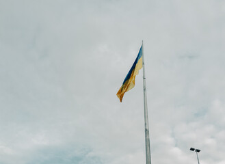 A flag with a yellow stripe and blue stripe is flying high in the sky