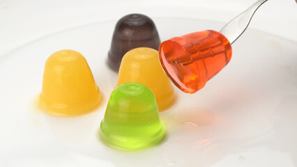 High angle view of assorted homemade small delicious fruit jelly in white ceramic plate on white background, closeup.