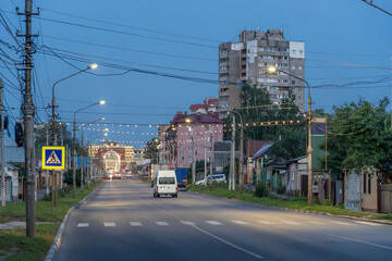 Fototapeta premium The night streets of Kursk, Russia, with the empty road, Soviet building, and city lights. 