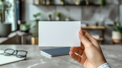 Empty paper card, blank notebook, eyeglass and laptop on marble desk background, top view