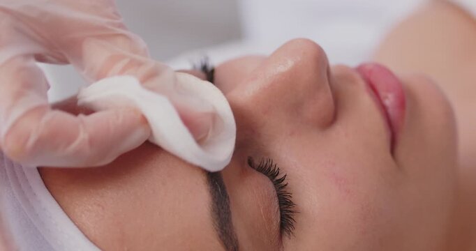 Cosmetologist delicately prepares between eyebrows and forehead of woman for Botox procedure. Close up of doctor in gloves touching woman's face. Concept of attention to detail in cosmetic procedures.