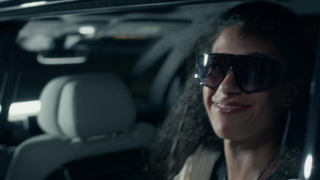 Beautiful Biracial pop diva in black sunglasses signing autograph to fan awaiting her by car at night