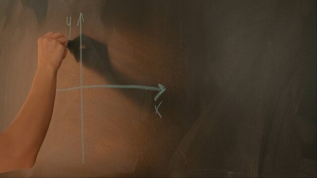 Close up of woman hand drawing coordinate axis with parabola on chalkboard, professor writes on blackboard or student solving task. Education and science concept.