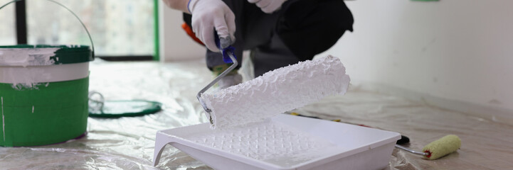 Male builder in uniform holding roller with white paint © megaflopp