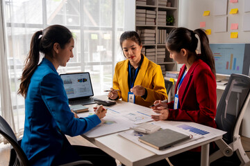 Three women are sitting at a table, discussing something