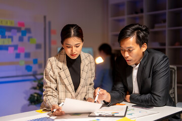 Two people are sitting at a desk looking at a piece of paper