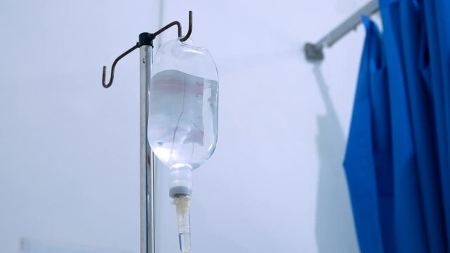 close up view of saline IV drip bag and Infusion pump hanging on stainless pole in the patient room at the hospital