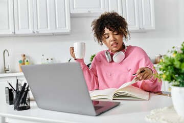 A cheerful woman immersed in study while sipping coffee at her kitchen table.
